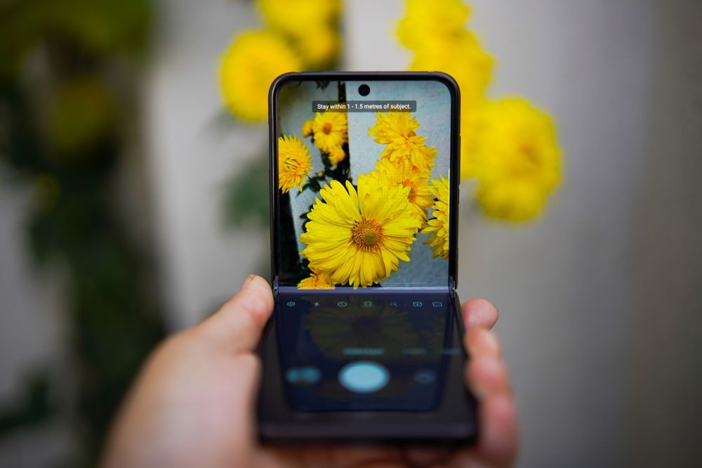 Mano che tiene uno smartphone pieghevole aperto, mostrando lo schermo grande, con un altro smartphone chiuso in primo piano.