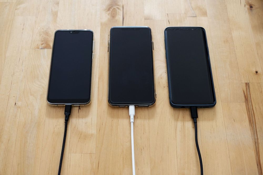 Persona che ricarica velocemente uno smartphone con cavo USB-C, mostrando l'icona della batteria in ricarica rapida.
