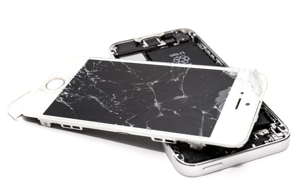 Tecnico che lavora alla riparazione del display di uno smartphone aperto con strumenti di precisione.