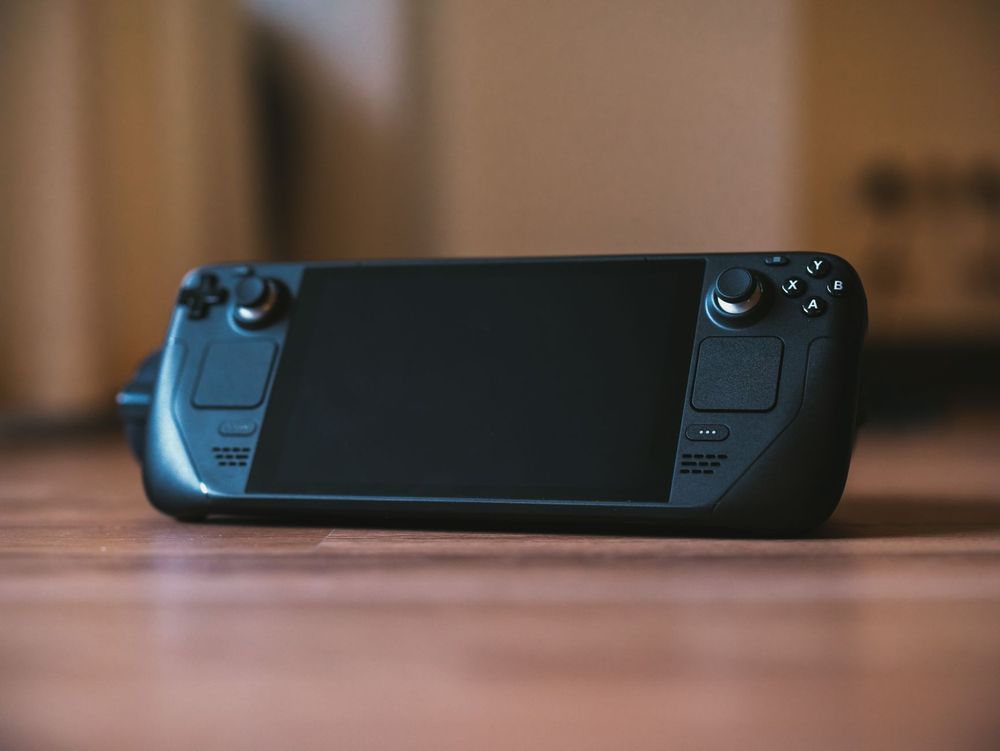 Primo piano di una persona che gioca con una console portatile pc seduta sul divano di casa.